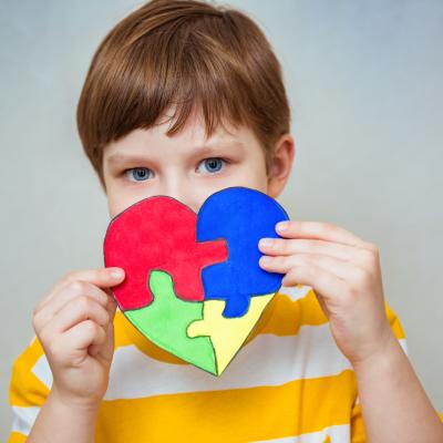 Kid boy holding a puzzle heart signifying world autism day