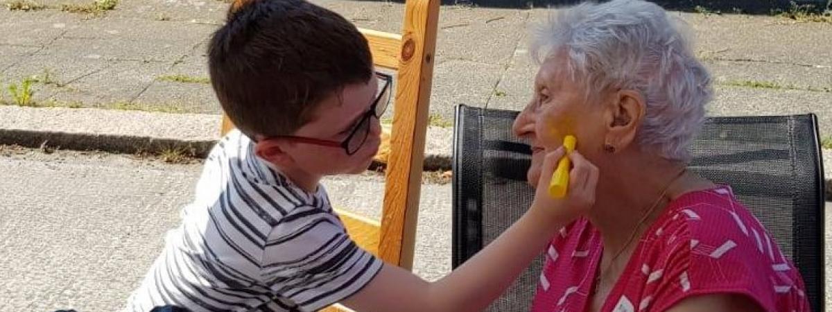 little boy paints older disabled womans face at street party  held as part of The Big Lunch