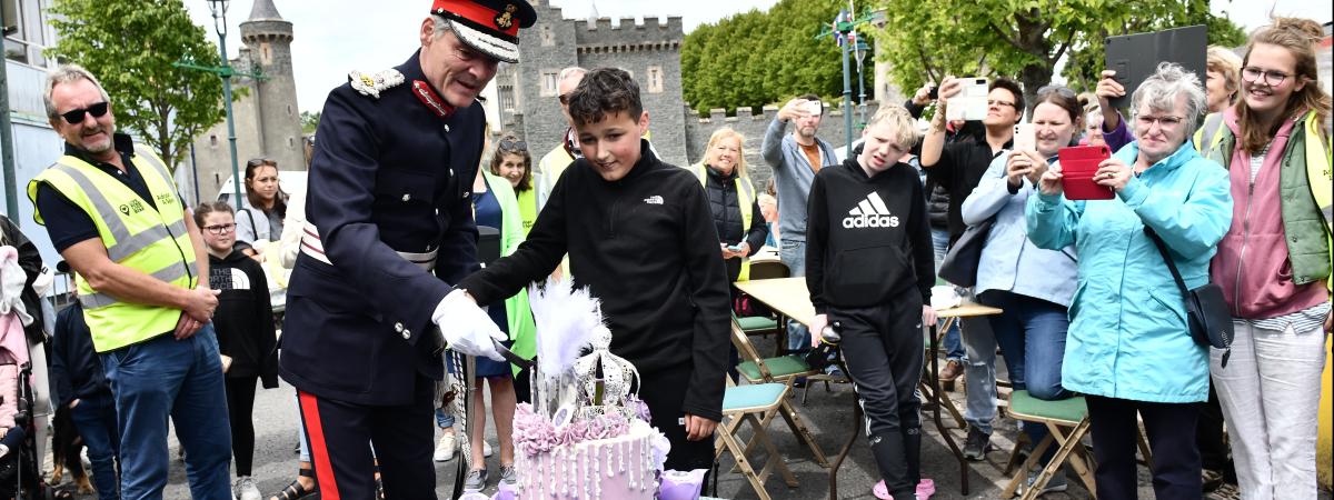 Lord Lieutenant Gawn Rowan Hamilton cuts the cake with the help of Tyson Chaddock at The Big Jubilee Lunch at Killyleagh on Sunday. An idea from Eden Project Communities, made possible by The National Lottery, The Big Jubilee Lunch is an official part of Her Majesty The Queen's special Platinum Jubilee celebration.