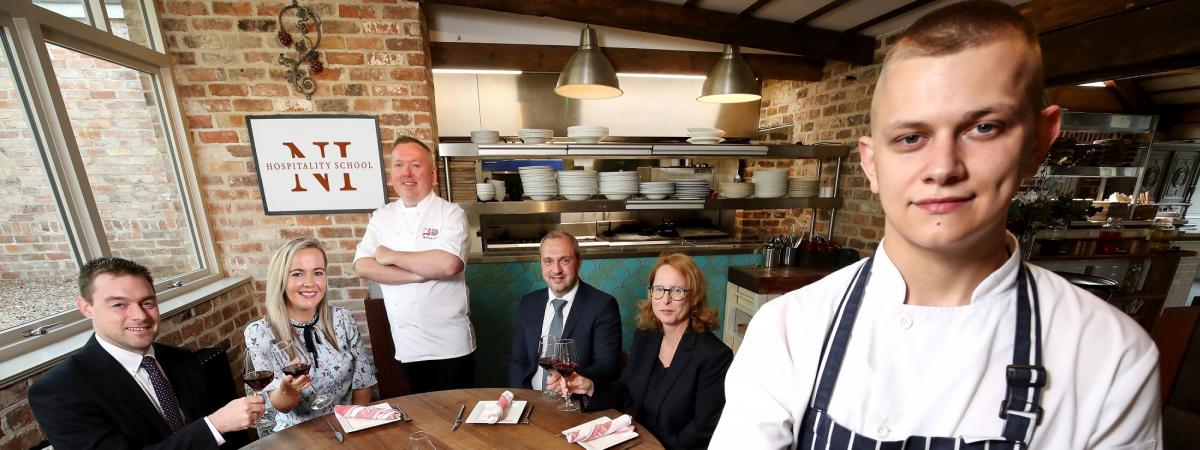 Chef holding plated food while people sit in the background