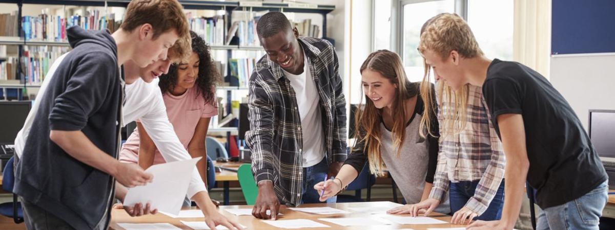 Young people standing at a desk working together on a project.