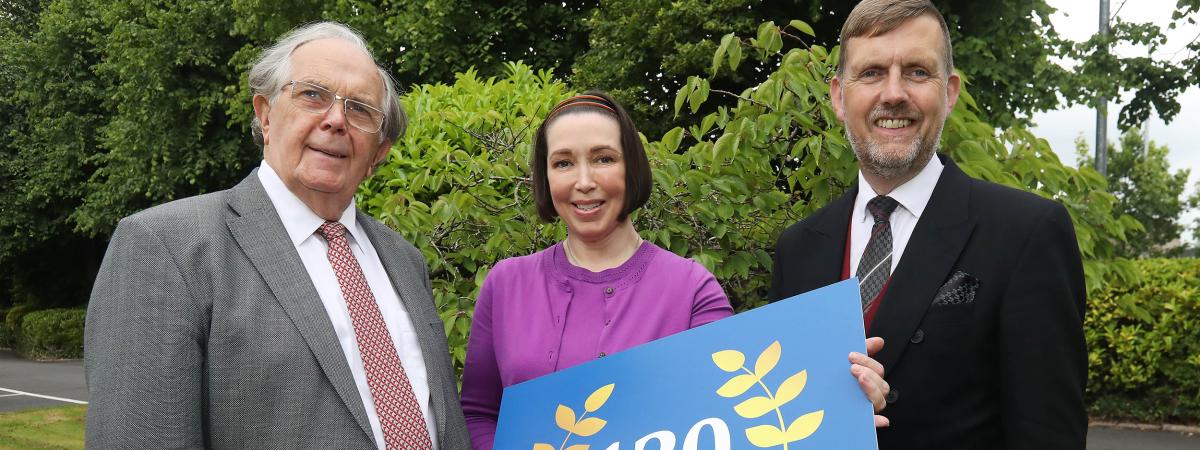 Three people hold up a sign celebrating 120 years of James Brown & Sons