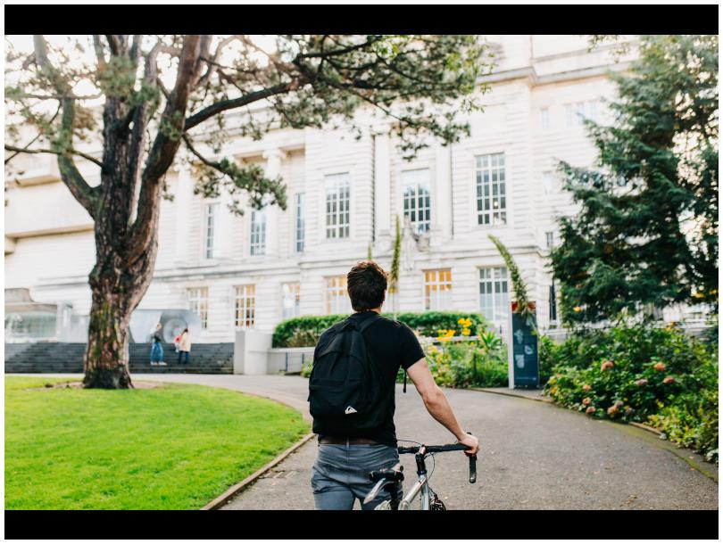 Man walking with bike towards museum building