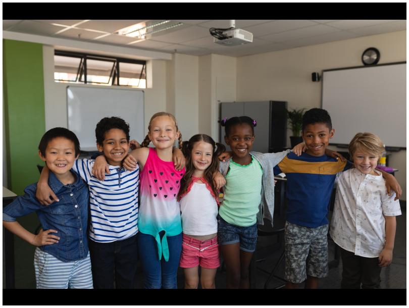 Happy school kids standing and looking at camera. Mixed ethnicities.