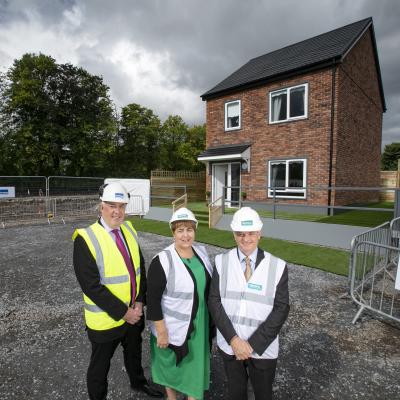 Eugene Lynch, Managing Director of The McAvoy Group, Clare McCarty, Group Chief Executive at Clanmil Housing and David Orr, Chief Executive of the National Housing Federation in front of a prototype house at Clanmil's site in Carrickfergus, where 40 new social homes will be the first in Northern Ireland delivered using off-site construction.