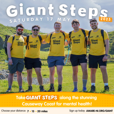 A promotional image featuring 4 men wearing AWARE NI t-shirts, walking boots and backpacks with the backdrop of the Causeway Coastline, accompanied by the text 'take Giant Steps along the stunning Causeway Coast for mental health'. The image also includes details about the sponsored 7, 13 or 20-mile coastal hike happening on Saturday 17 May, and the website aware-ni.org/giant to sign up today!